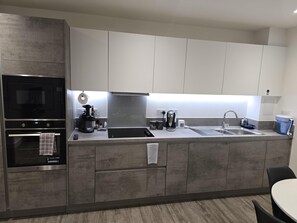 A modern kitchen with a built-in oven, microwave, and coffee maker. - Luxurious 2-bed Haven in the Heart of Barking (Barking)