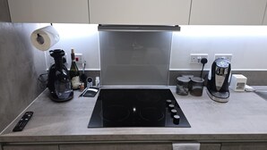 Une cuisine équipée d’une plaque de cuisson à induction noire, d’une machine à café et d’un rouleau d’essuie-tout.