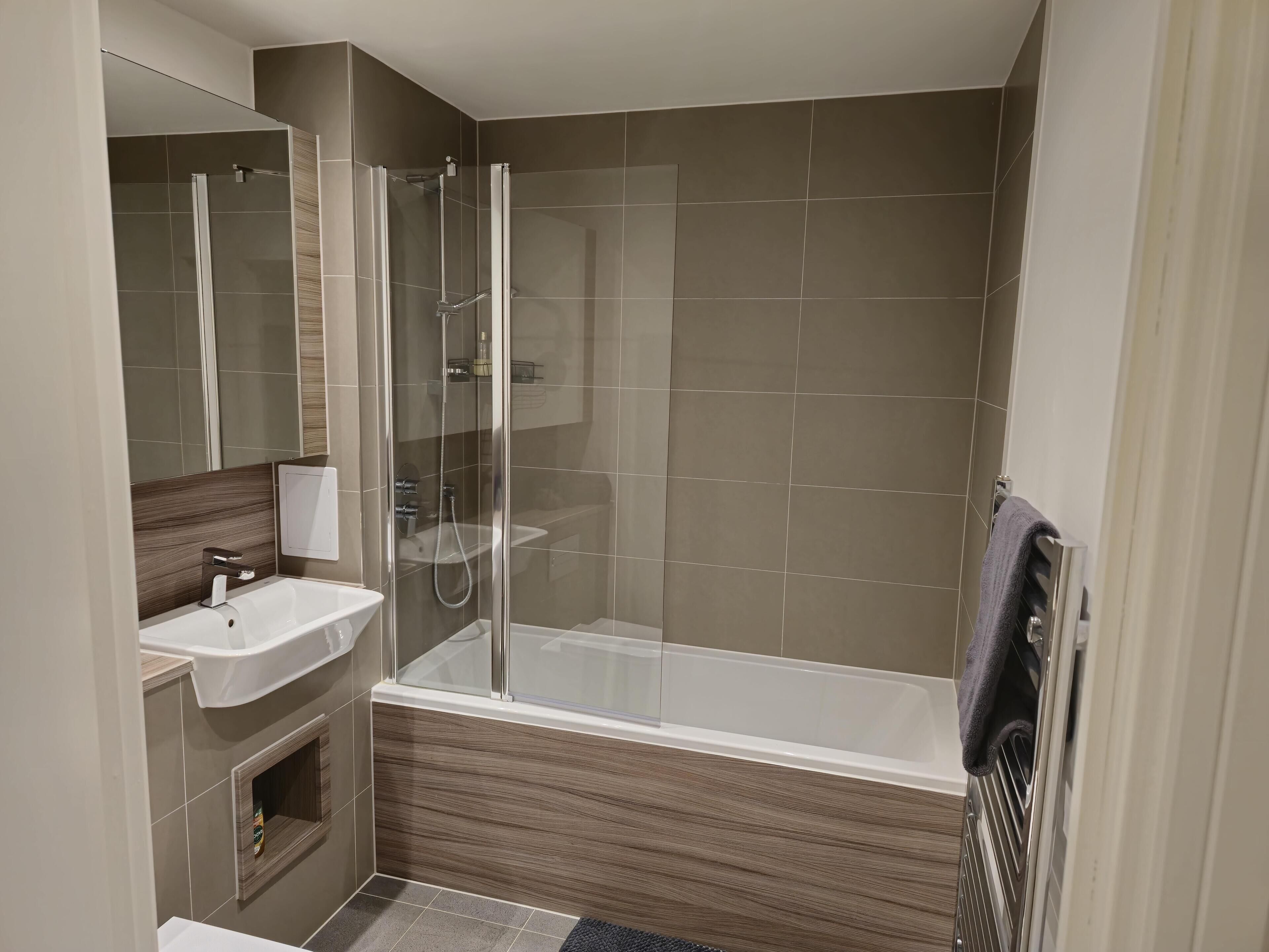 A modern bathroom with a glass-enclosed shower, a sink, and a bathtub.