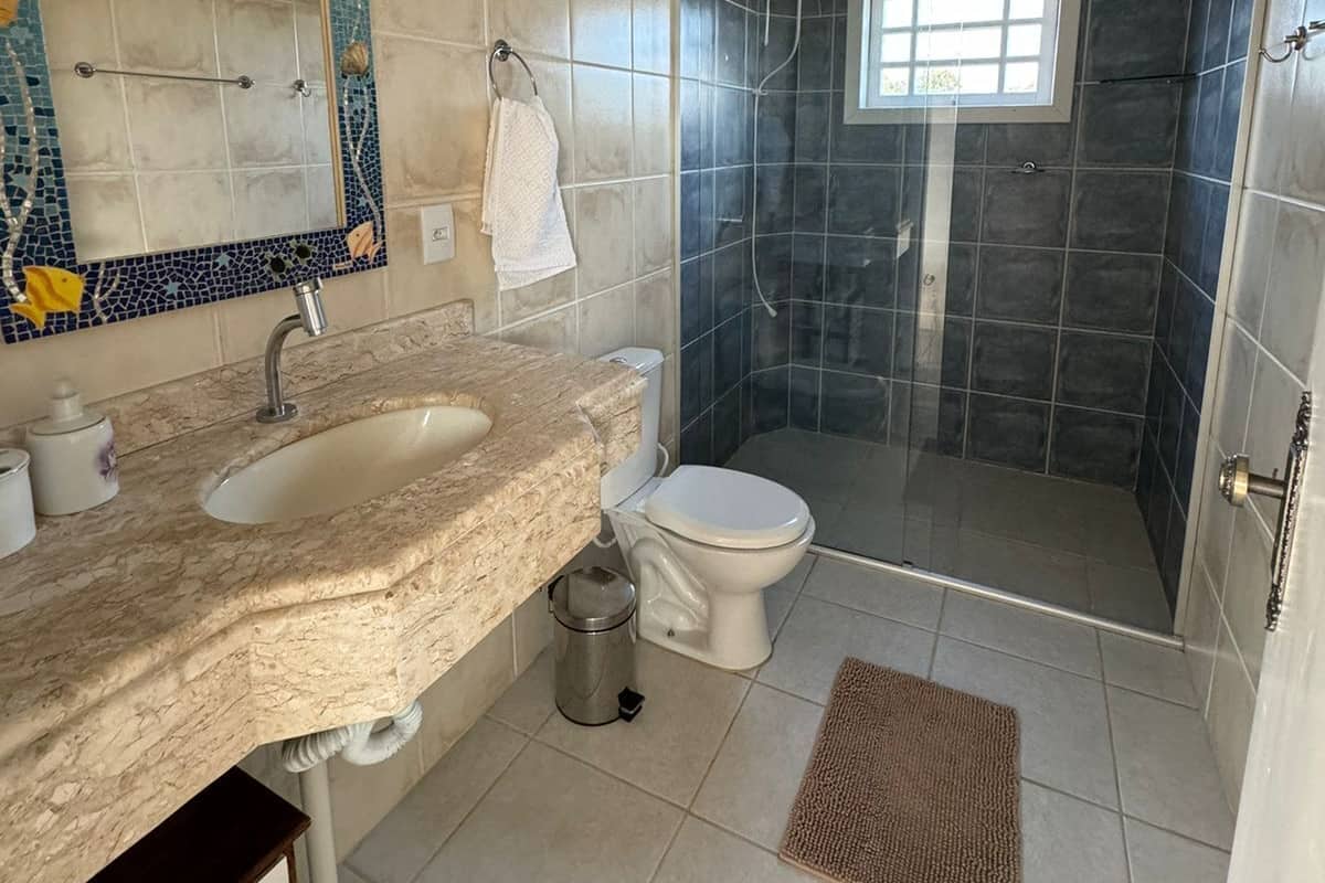 A bathroom with a double sink vanity, a toilet, a shower enclosure, and a small window.