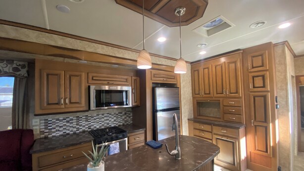 Une cuisine moderne avec des meubles en bois, des appareils électroménagers en acier inoxydable et des luminaires suspendus.