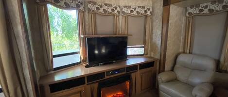 Ein gemütliches Wohnmobil-Interieur mit Fernseher, Kamin und Ledersofa.