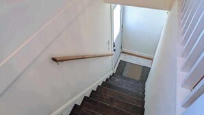 A staircase with wooden steps and a metal handrail, leading to an upper floor.