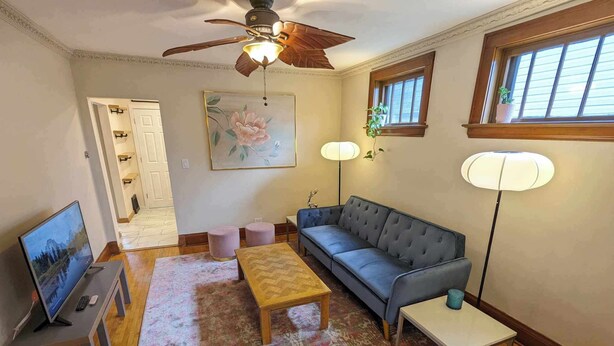 Una sala de estar con sofá, mesa de centro, televisor y ventilador de techo.