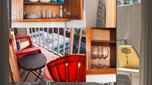 Une cuisine compacte avec des meubles en bois, un coin repas avec des chaises rouges et une vue sur la ville depuis un balcon.