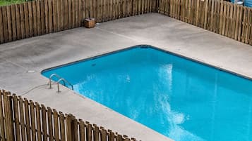 A rectangular swimming pool with a wooden fence surrounding it.