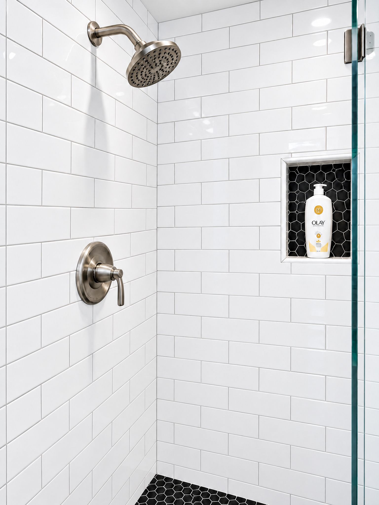 A shower with a handheld showerhead and a wall-mounted faucet.