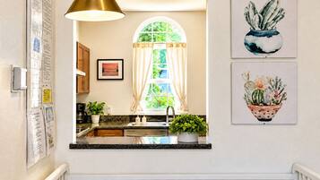 A kitchen with a window, a sink, a countertop, and a hanging light fixture.