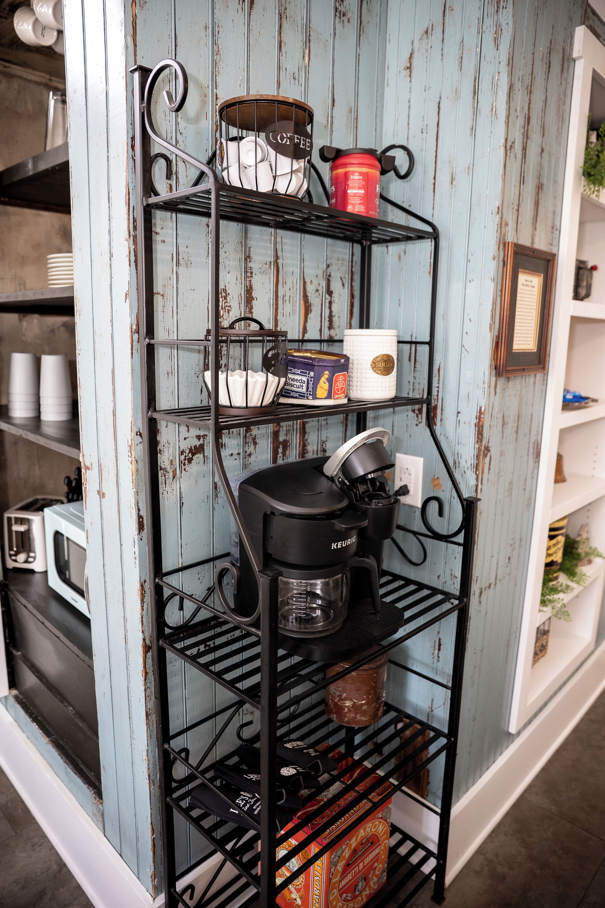 A kitchen shelf with various kitchen items including a coffee maker, tea pots, and containers.