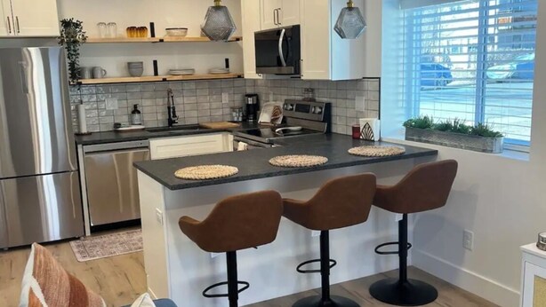 Una cucina moderna con isola centrale, sgabelli da bar e un divano blu in zona living.