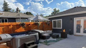 Un giardino con idromassaggio, area salotto esterna, recinzione in legno e una casa.