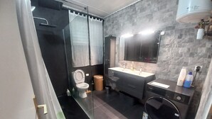 Une salle de bain moderne équipée d’un WC, d’un lavabo, d’un miroir et d’un lave-linge.