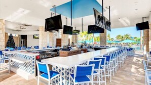 Zona de bar con diferentes opciones de asientos, una barra central y un árbol de Navidad.