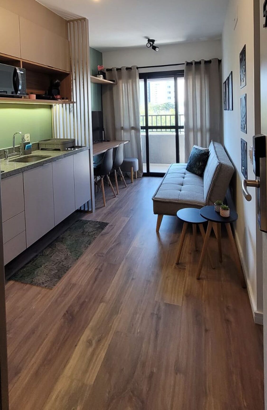 A modern apartment with a kitchen, dining area, and a living room with a sofa and a small table.