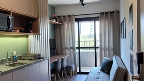 Eine moderne Wohnung mit Küche, Essbereich und Wohnzimmer inklusive Sofa und kleinem Tisch.