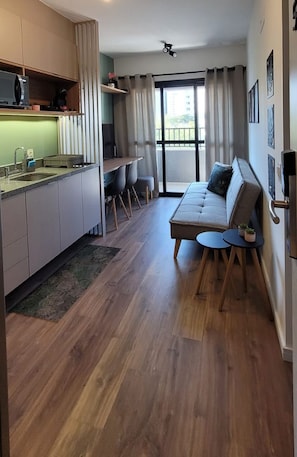 Eine moderne Wohnung mit Küche, Essbereich und Wohnzimmer inklusive Sofa und kleinem Tisch.