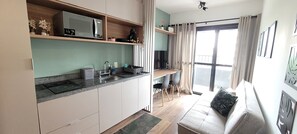 Une cuisine moderne équipée d’un four à micro-ondes encastré, d’un évier et d’un coin repas avec un canapé et des chaises.