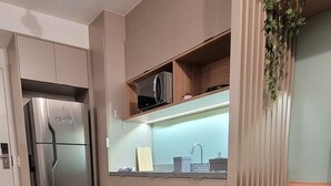 Eine moderne Küche mit integriertem Mikrowellenherd, einem Edelstahlkühlschrank und einem Holzespeisetisch mit Stühlen.