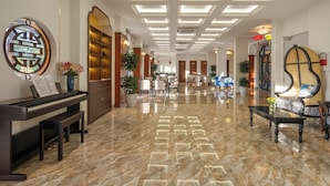 A spacious lobby with a piano, seating area, and a large mirror. - Soluna D'Annam - The Art of Hoi An Relaxation (Da Nang)