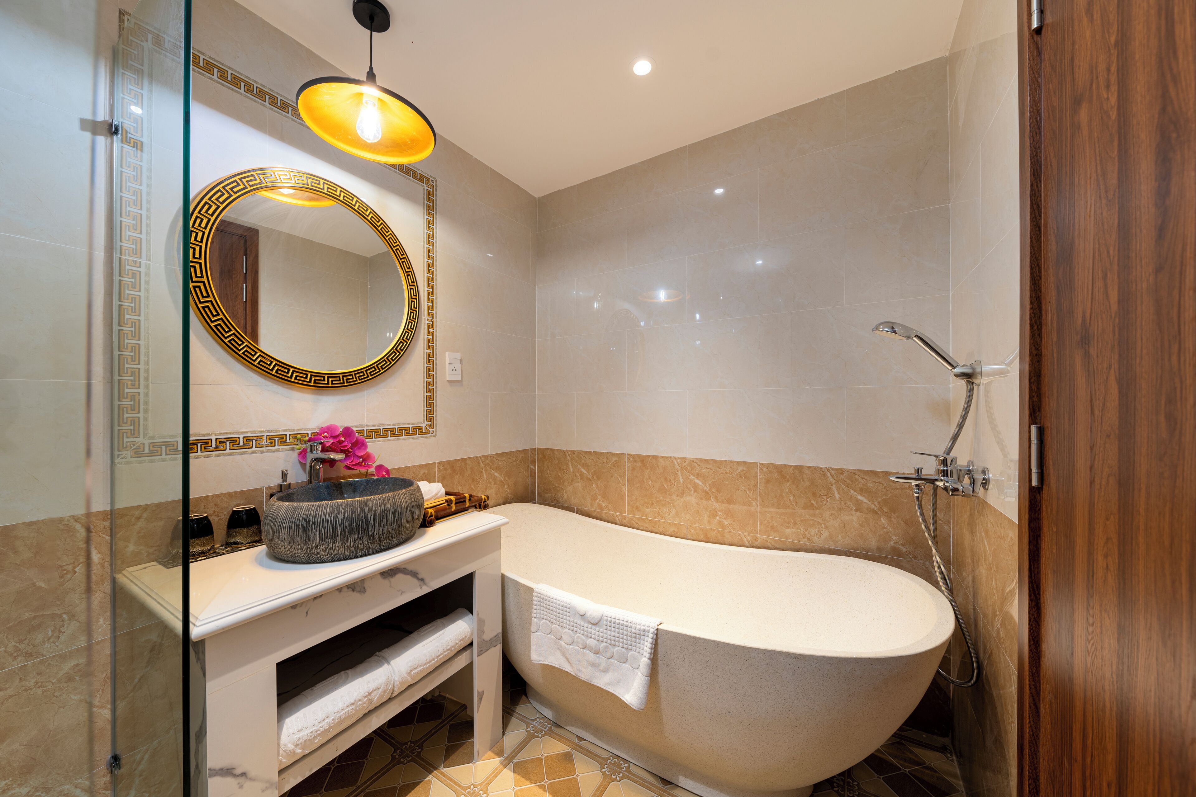 Un baño moderno con una bañera independiente, un tocador con un lavabo de estilo decorativo, un espejo grande con un marco decorativo y una zona de ducha.