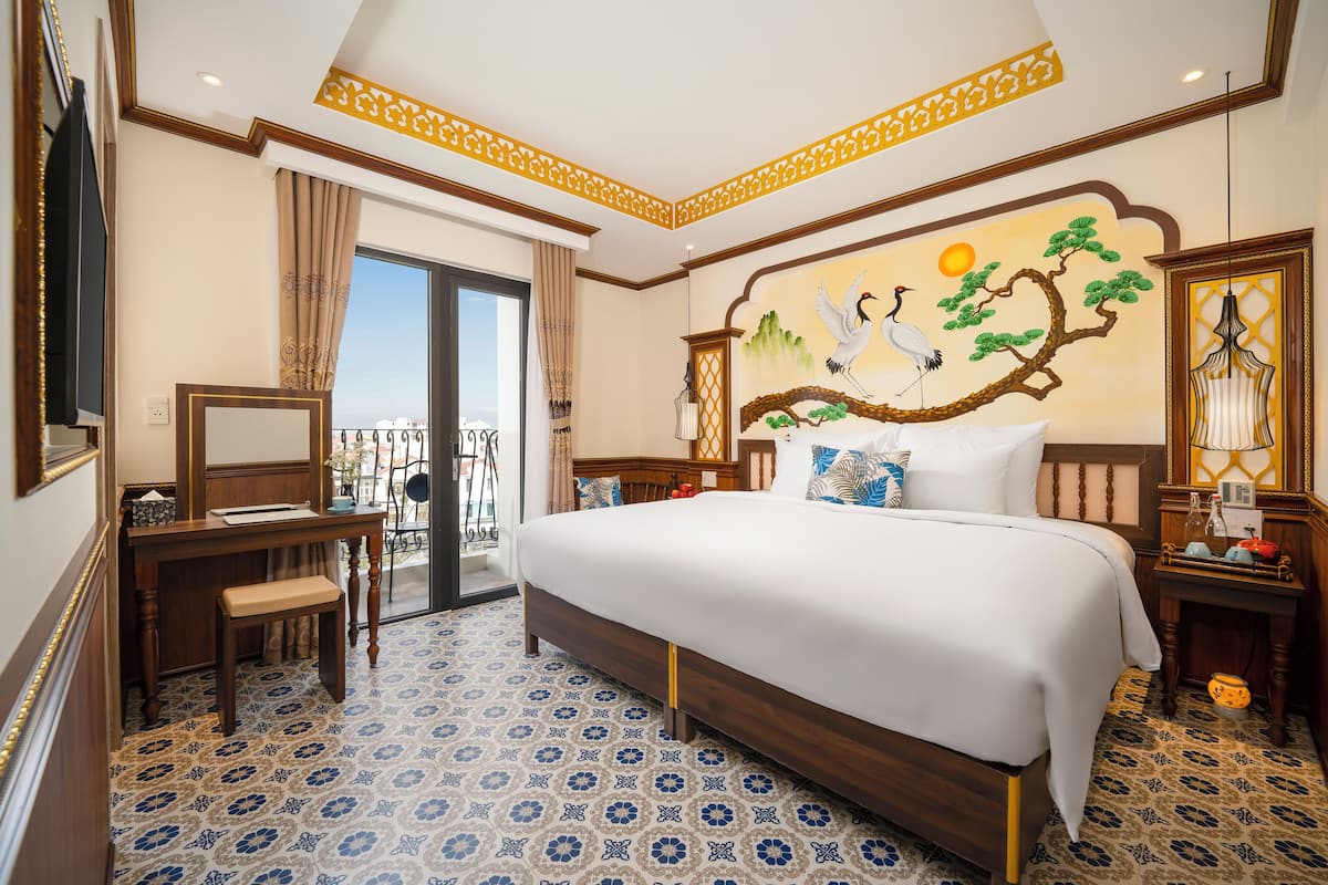 A hotel room with a large bed, a desk, and a view of the outdoors.