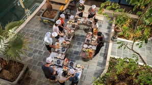 A rooftop restaurant with multiple tables and chairs, surrounded by potted plants and a pool. - Soluna D'Annam - The Art of Hoi An Relaxation (Da Nang)