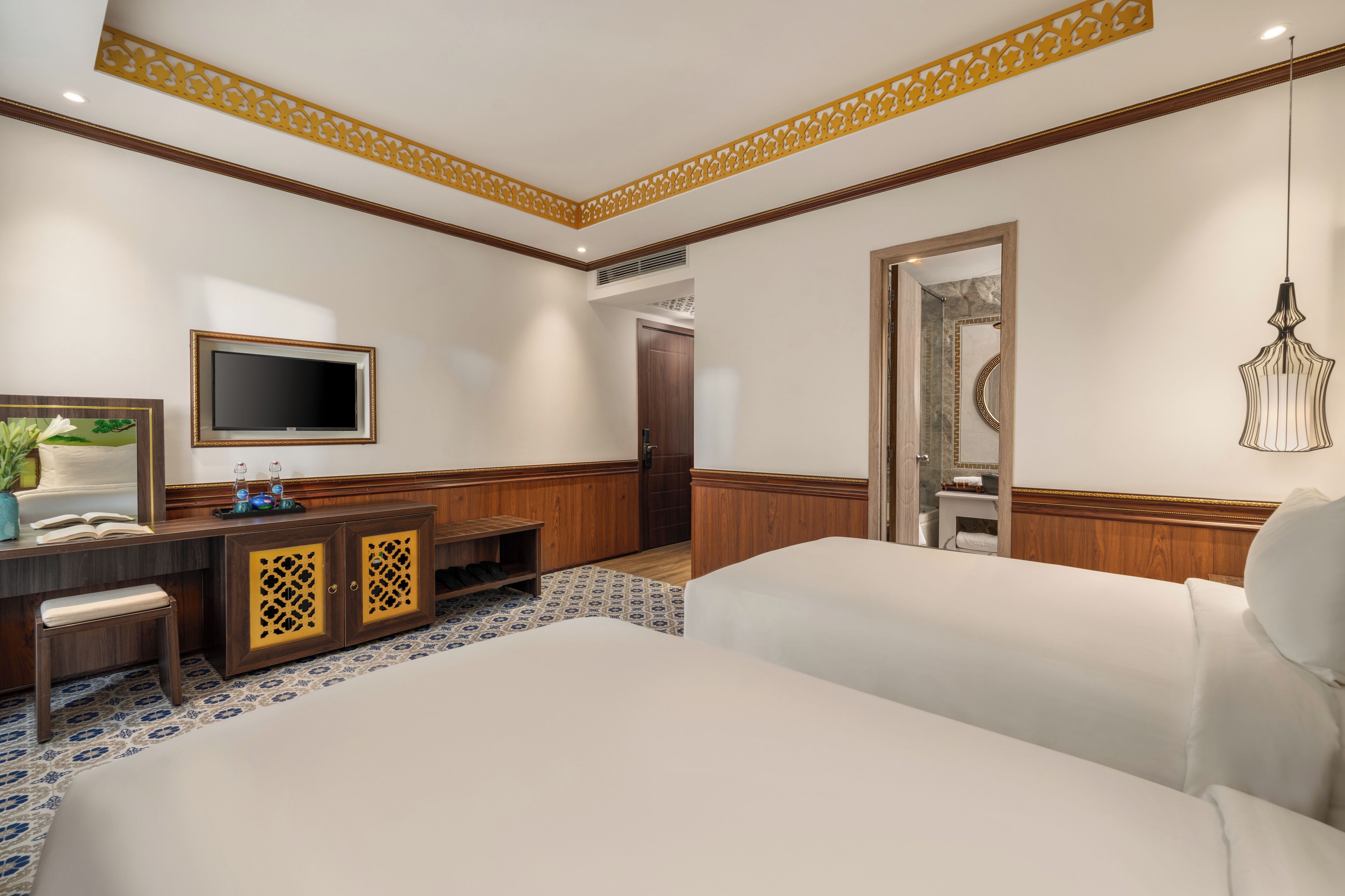 A hotel room with a bed, a desk with a TV, a small seating area, and a bathroom door.