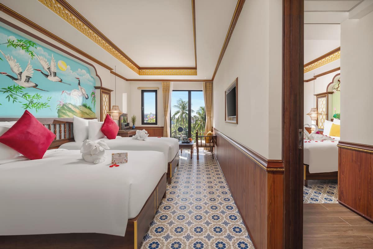 A hotel room with two beds, a mural, a view of palm trees, and a patterned floor.