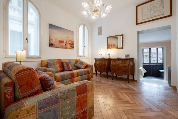 A cozy living room with a sofa, wooden cabinet, and artwork on the walls.