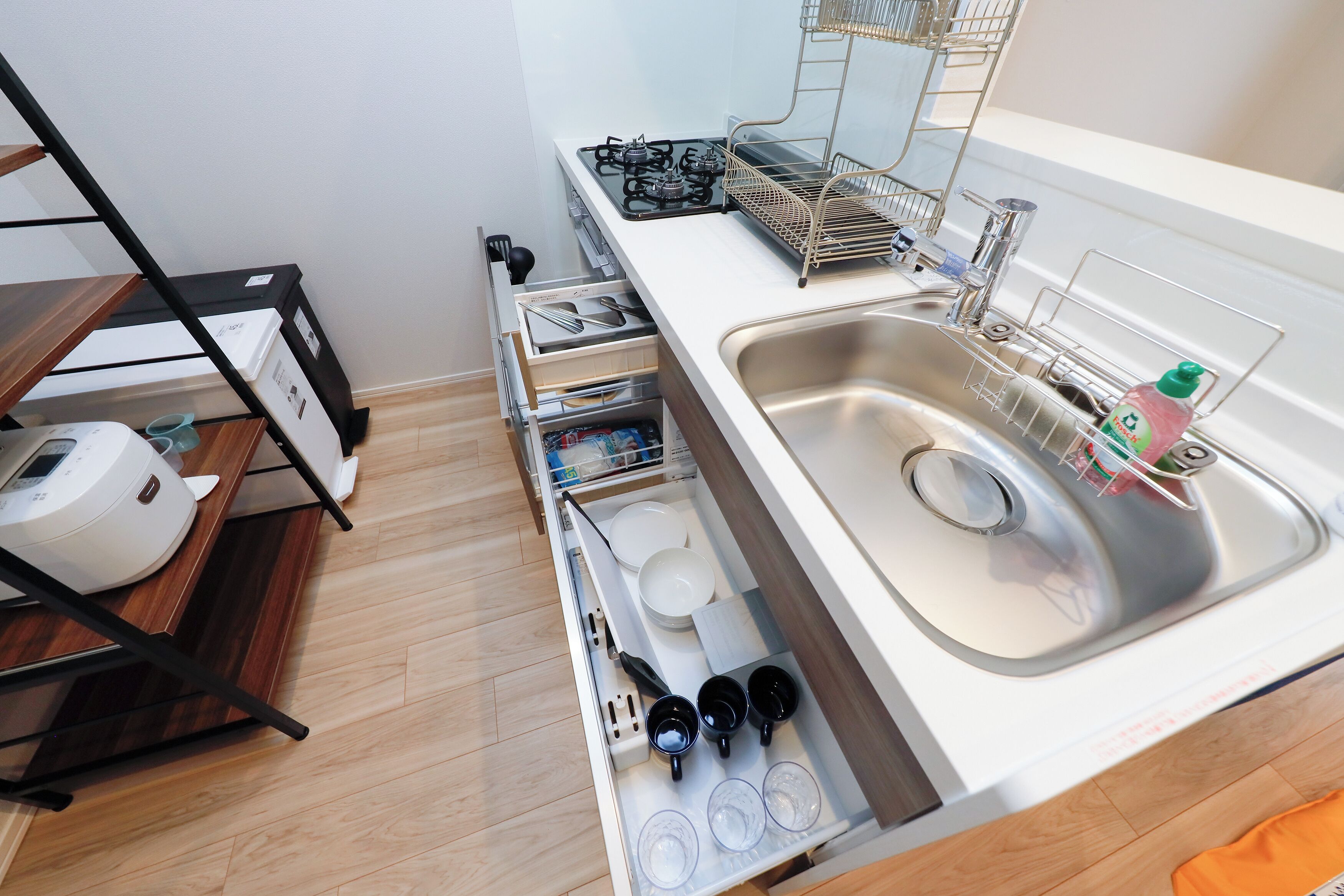 A kitchen with a built-in sink, a stove, and a drawer organizer with utensils and dishes.