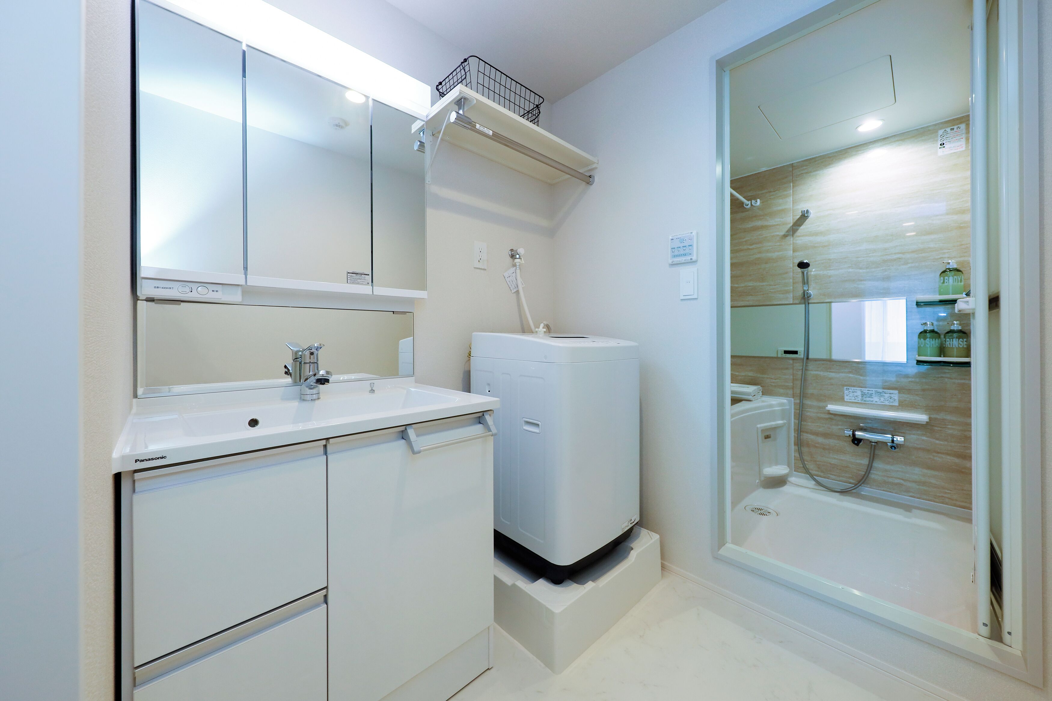 A bathroom with a sink, mirror, cabinet, and a walk-in shower.