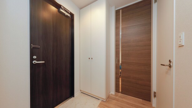 A hallway with a dark wooden door, a white door, and a light wooden floor. - La Terrasse Higashikomagata by Tranova (Tokyo)