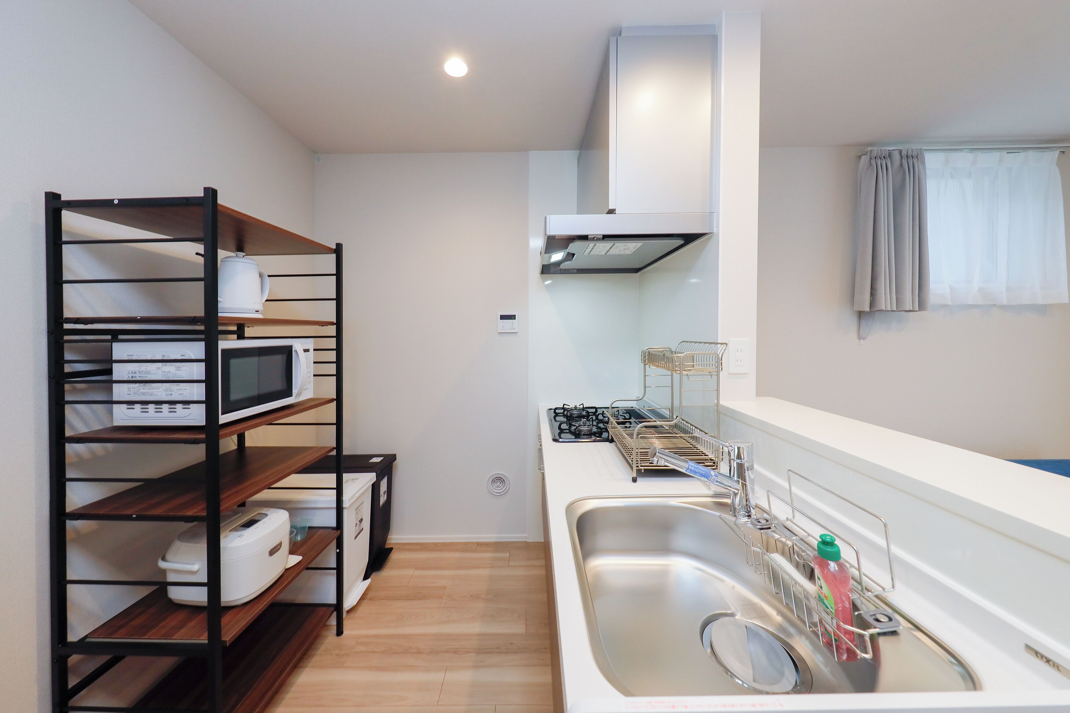 Una cocina compacta con microondas, estufa y lavamanos.