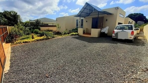 A modern house with a gravel driveway, a covered carport, and a small garden area.