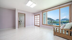 Ein geräumiger Raum mit großem Fenster, einer hölzernen Bank und einer Tür zu einem anderen Zimmer.