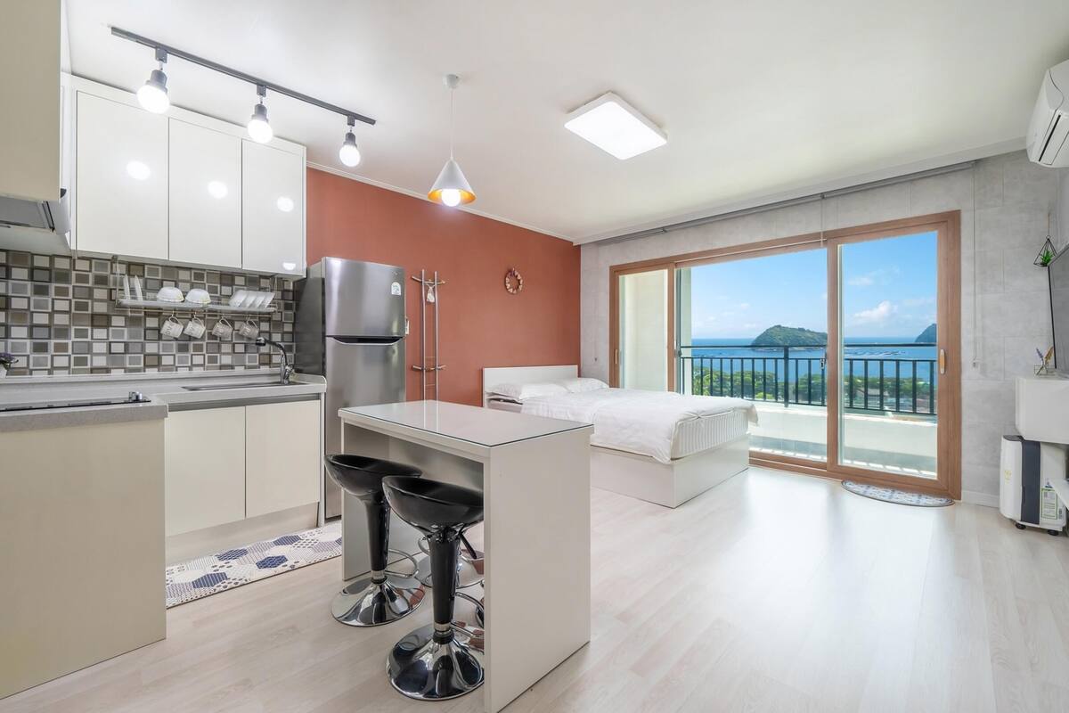A modern apartment with a kitchen, dining area, and a balcony with a view.