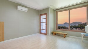 Ein Zimmer mit großem Fenster, einer hölzernen Bank und einer Tür mit satinierten Glasscheiben.