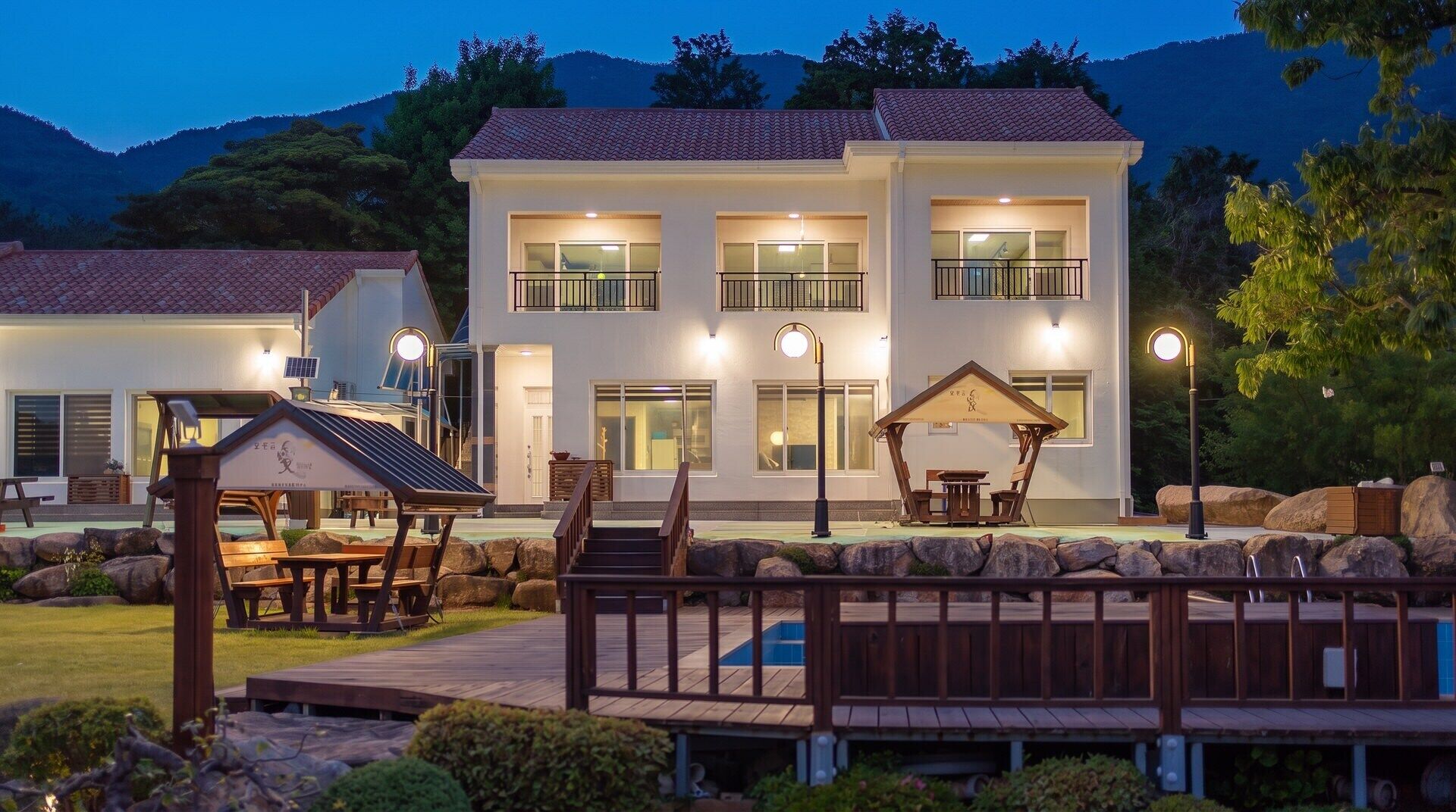 A two-story building with a balcony, a covered outdoor seating area, and a pool.