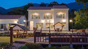 A two-story building with a balcony, a covered outdoor seating area, and a pool.