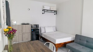A compact room with a bed, a sofa, a small kitchenette, and a wooden table. - Manhattan Bridge-Brooklyn-UN (Brooklyn)