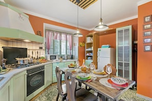 Een keuken met een eettafel voor vier personen, een fornuis, oven en diverse keukenapparaten.