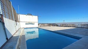 Une piscine sur le toit, avec un ciel bleu azur en arrière-plan.