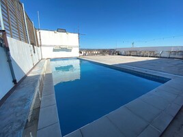 Una piscina en la azotea con un cielo azul despejado al fondo.