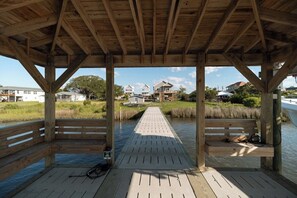 A wooden deck with benches, a pathway leading to a grassy area, and houses in the background.