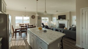 A spacious kitchen with a large island, dining area, and a fireplace. - New! Intracoastal Cottage with Dock! (Surf City)