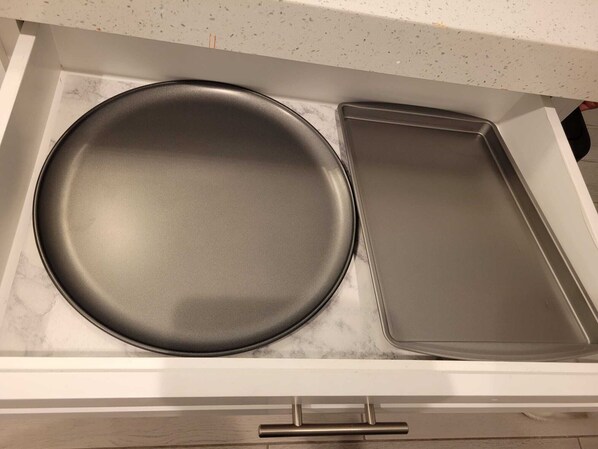 A kitchen drawer with a round baking pan and a rectangular baking tray.