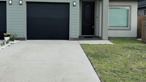 Une maison de plain-pied avec une porte de garage sombre, une porte d’entrée et un petit porche.
