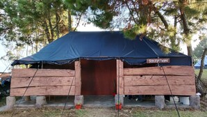 A rustic wooden structure with a dark blue tarp roof and a sign labeled "RECEPTION".