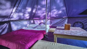 A tent with a bed, a table, and a bench.