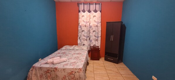 Un dormitorio con cama, armario y cortina.